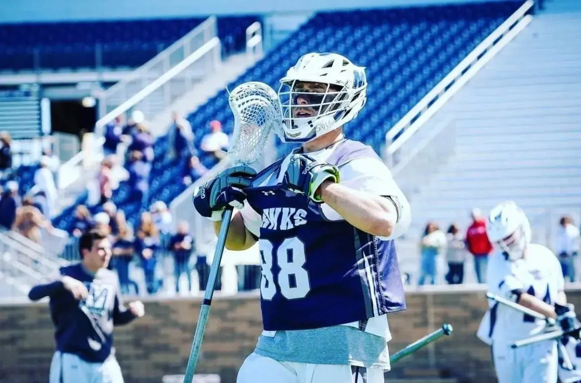 A lacrosse player is holding his stick up to the side.