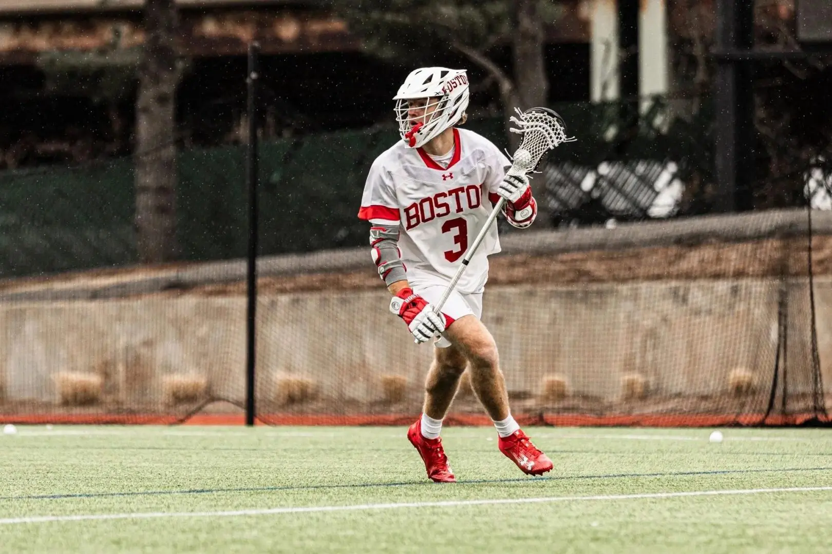 A lacrosse player is running on the field.