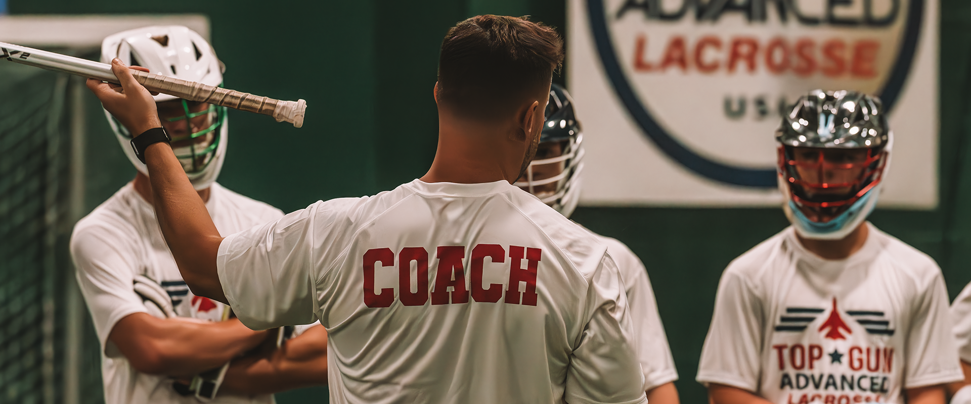 A baseball coach is holding his bat in the air.