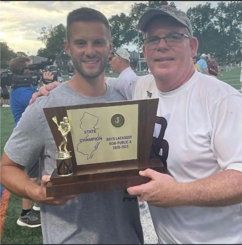 Two men holding a trophy and smiling for the camera.