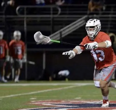 A lacrosse player is running with the ball.