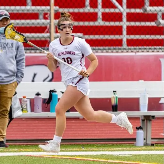 A female lacrosse player running on the field