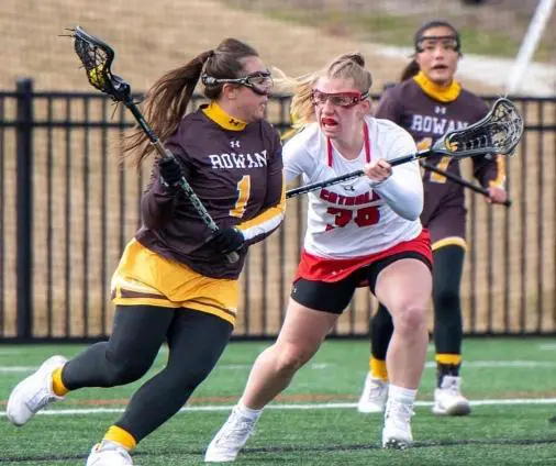 A group of girls playing lacrosse on the field.