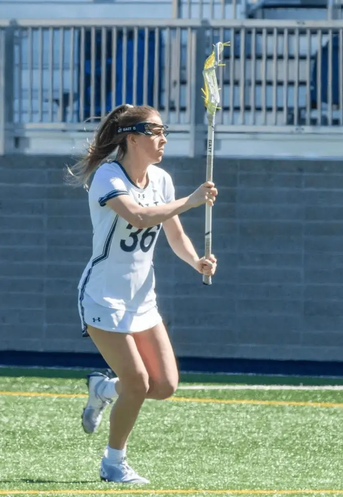 A girl holding a lacrosse stick on top of a field.