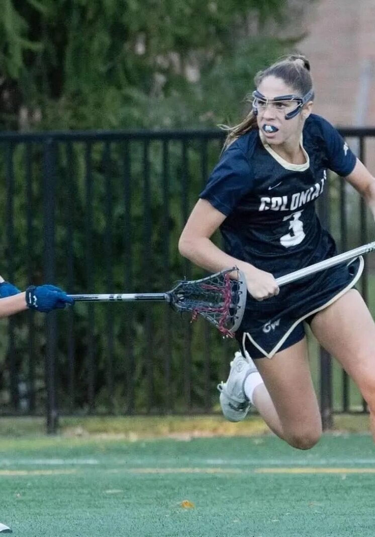 A woman running with a lacrosse stick in her hand.