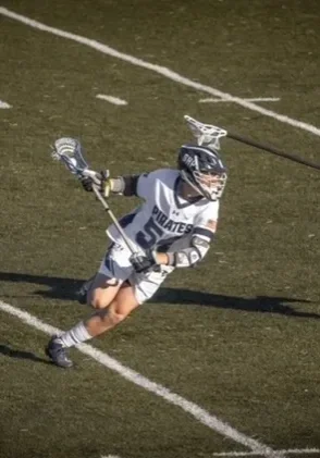 A lacrosse player is running with the ball.