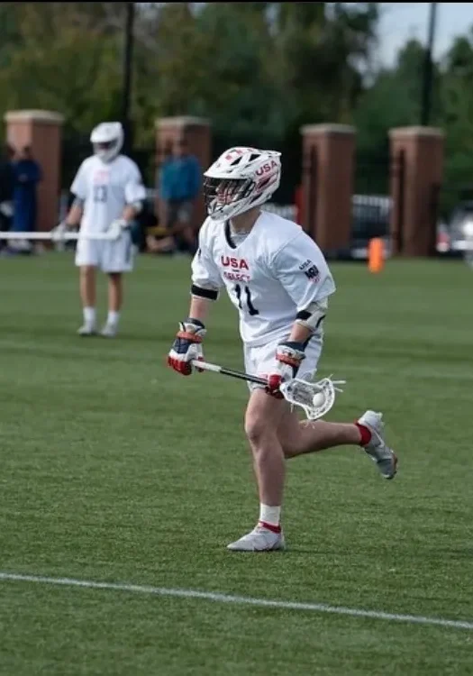 A lacrosse player running across the field.