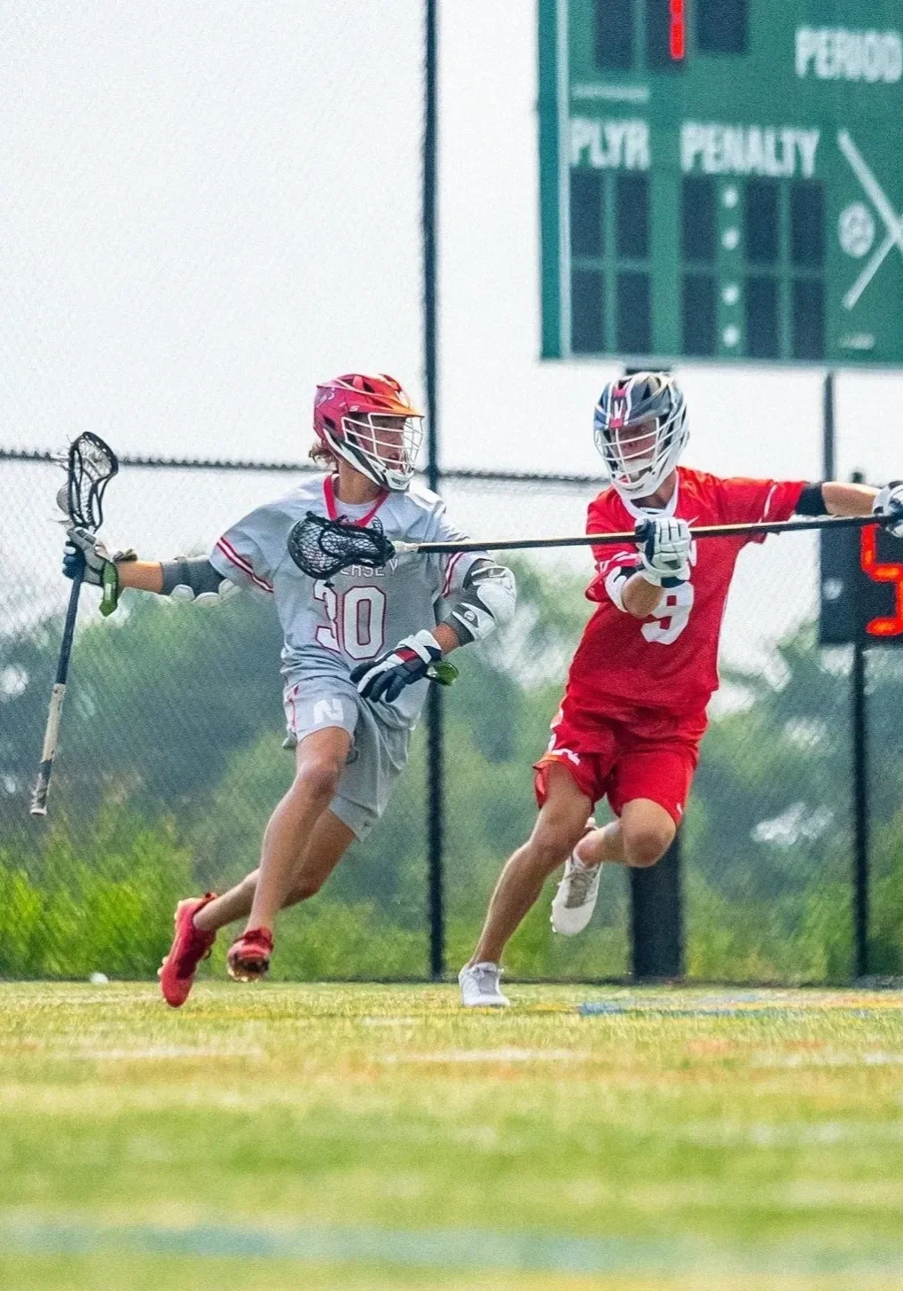 Two lacrosse players are running on a field.