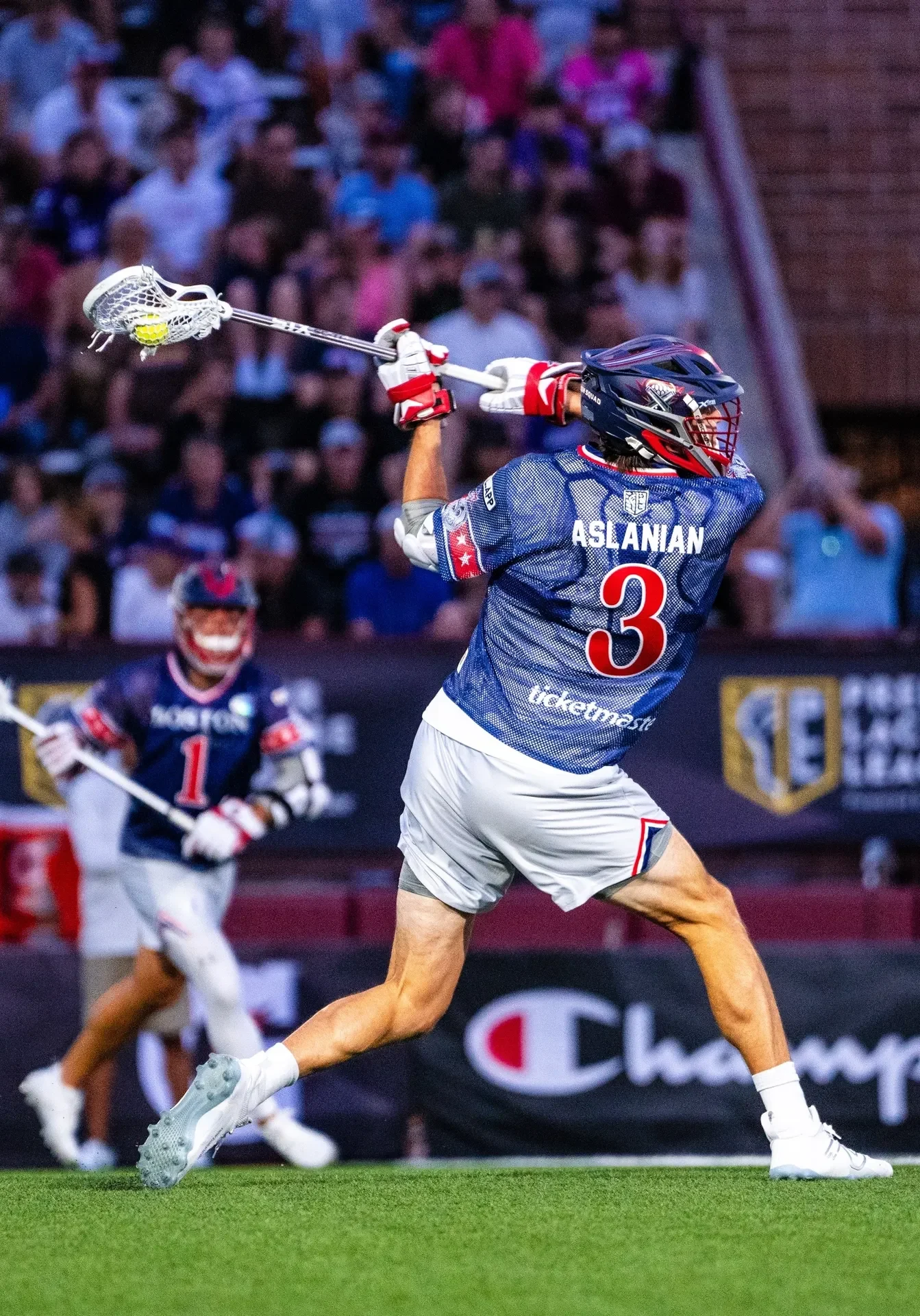 A lacrosse player is in the air with his stick.