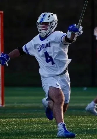 A lacrosse player is running on the field.