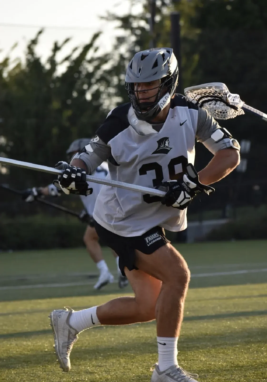 A lacrosse player is running with the ball.